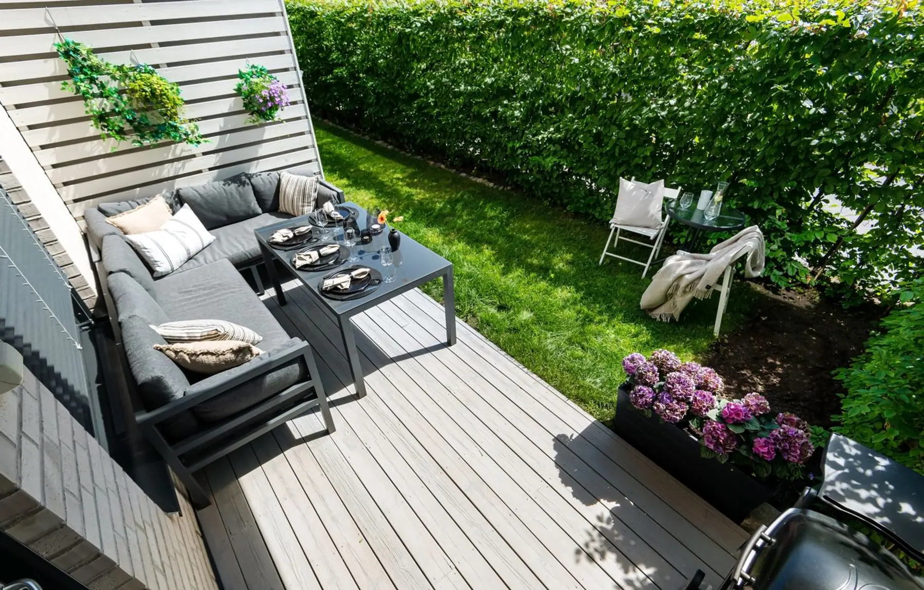 Moderne Holzterrasse mit Loungemöbeln und angrenzendem Rasen