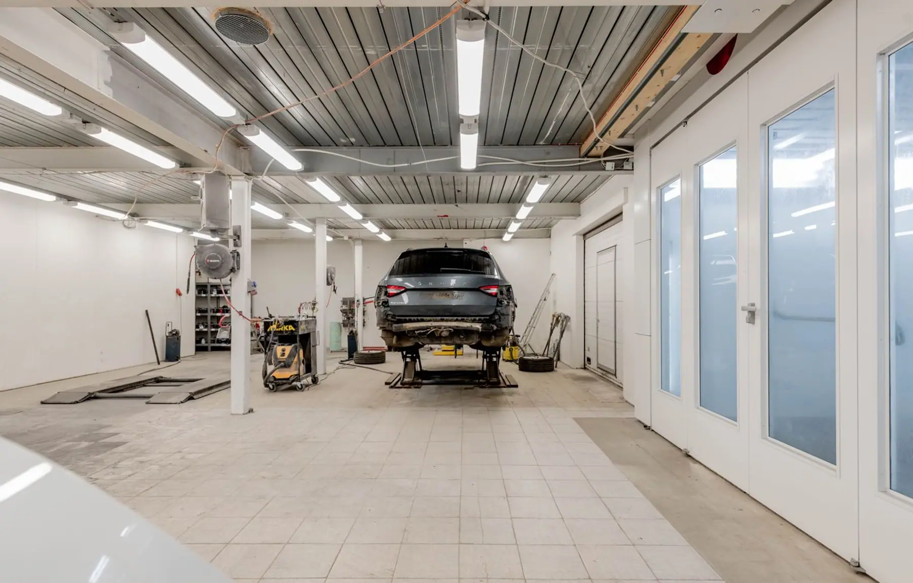 Aufgeräumte Werkstatthalle mit Fahrzeug auf der Hebebühne