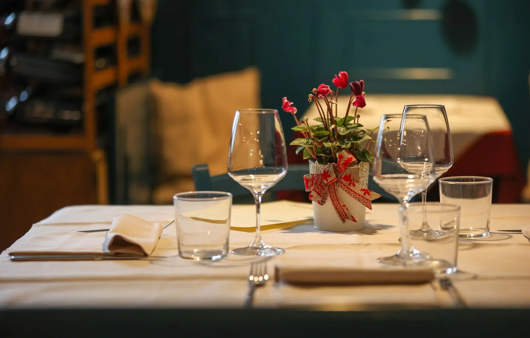Gedeckter Tisch mit Weingläsern und frischen Blumen im warmen Abendlicht